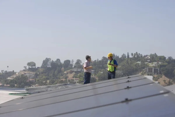 Рабочие обслуживания стоят с солнечной батареей на крыше — стоковое фото