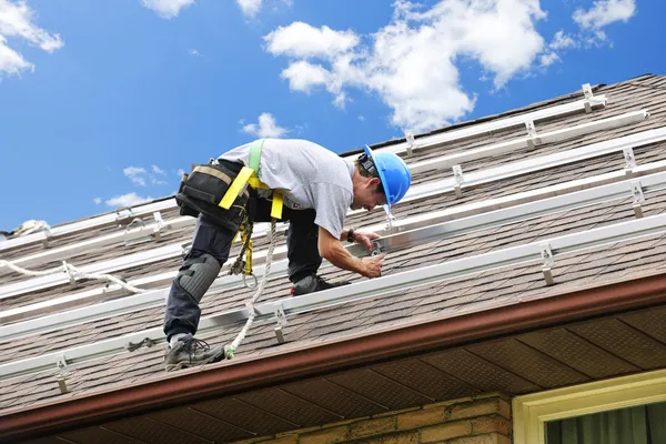 Человек, работающий на крыше установки рельсов для солнечных панелей — стоковое фото